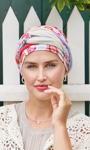 Woman wearing a printed turban with a white picket fence background.