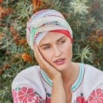 Woman wearing a colorful printed turban with floral background.
