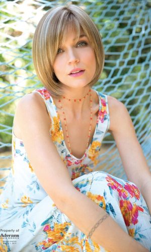 Woman with a short, layered bob wig in a sunny outdoor setting.