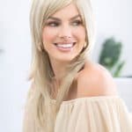 Beautiful blonde layered wig styled on smiling woman with off-shoulder top.