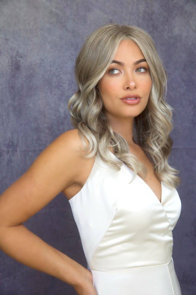 Woman with long, silver wavy wig and natural makeup.