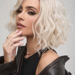 Blonde wavy wig styled on a woman with makeup and leather jacket.