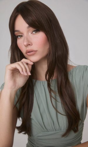 Beautiful woman with long, wavy brown wig and natural makeup.