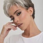 Stylish short gray wig on a woman with makeup and jewelry.