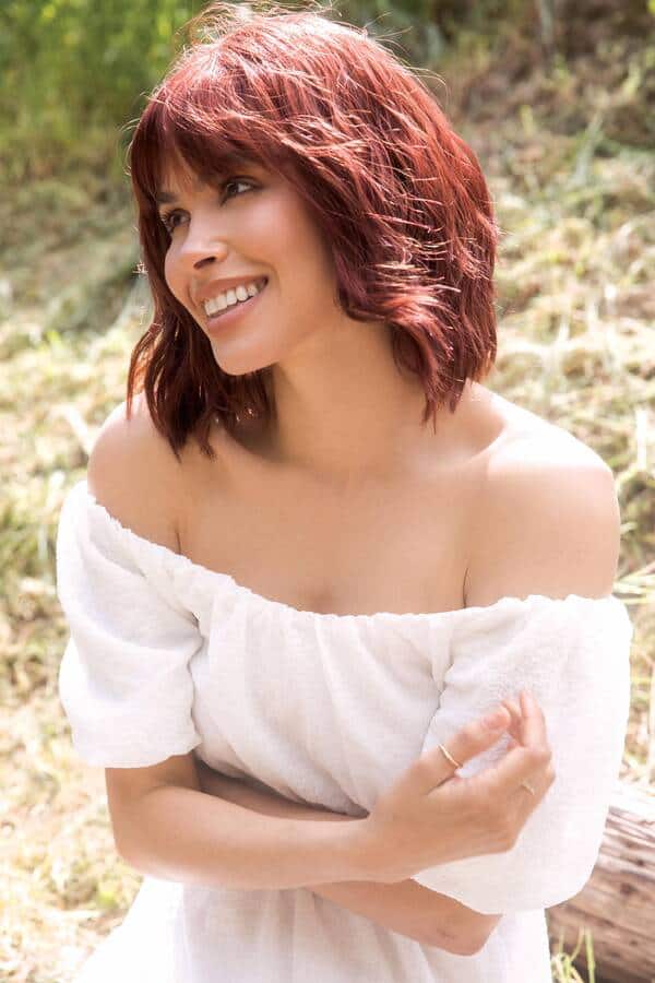 Red wavy bob wig on smiling woman outdoors, natural look, stylish hairpiece.