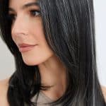 Close-up of a woman wearing a sleek black wavy wig with natural shine.