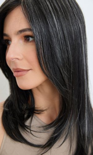 Close-up of a woman wearing a sleek black wavy wig with natural shine.