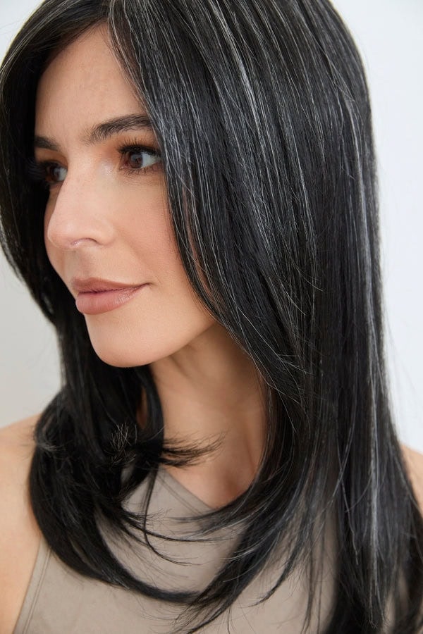 Close-up of a woman wearing a sleek black wavy wig with natural shine.