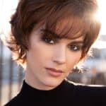 Short brown wig styled on a woman with side-swept bangs and layered cut.