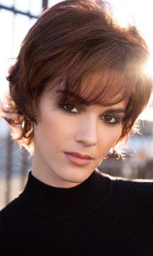Short brown wig styled on a woman with side-swept bangs and layered cut.