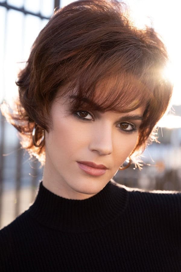 Short brown wig styled on a woman with side-swept bangs and layered cut.