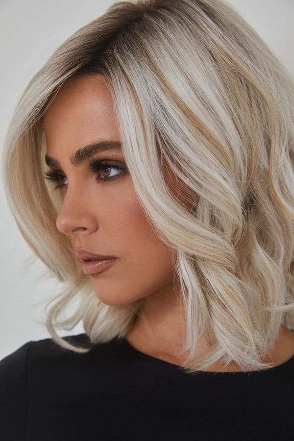 Blonde wavy wig styled on a woman with side parting and soft curls.