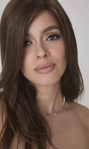 Beautiful woman wearing a long, wavy brown wig with natural highlights.