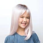Young girl with long, straight, platinum blonde wig smiling.