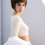 Fashion model with short brown wig in a white top and jacket, stylish and modern look.