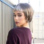 Fashion model with short, layered wig in urban setting for Hidden Secrets Wigs.