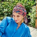 Woman wearing a vibrant, multicolored boho turban with a blue top.