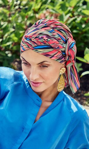 Woman wearing a vibrant, multicolored boho turban with a blue top.