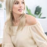 Blonde wig from Hidden Secrets Wigs on a woman with a beige off-shoulder top.