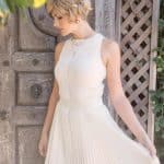 Blonde short wavy wig on woman in white dress outdoors.
