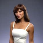 Wavy brown wig with side-swept bangs on a woman in a white dress.