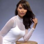 Elegant woman with long, wavy hair wearing a white top and hoop earrings.
