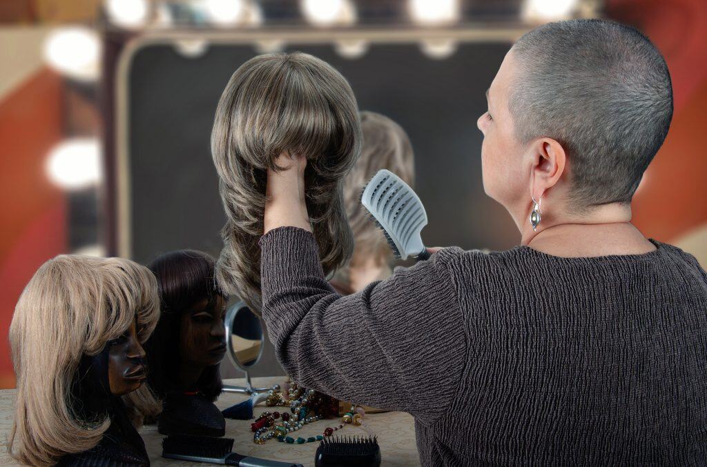 Woman styling wig on mannequin at Hidden Secrets Wigs salon.