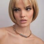 Blonde bob wig styled on a woman with makeup and jewelry.