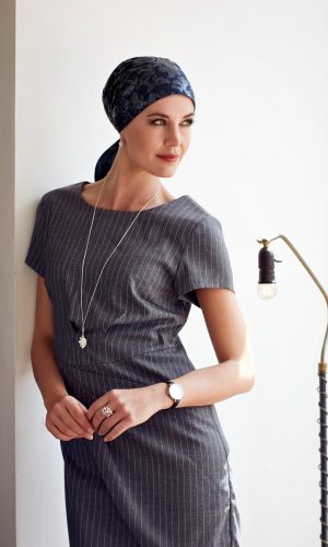 Woman wearing a short scarf wig with a gray pinstripe dress and accessories.