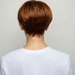 Back view of a woman with a short, layered auburn wig from Hidden Secrets Wigs.