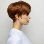 Side view of a woman with a short, layered auburn wig from Hidden Secrets Wigs.