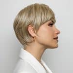 Side view of a woman wearing a short blonde wig with layered style.