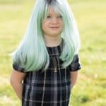 Child wearing mint green and silver wig outdoors for Hidden Secrets Wigs.