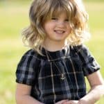 Child with blonde wavy wig from Hidden Secrets Wigs.