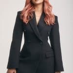 Stylish woman with pink wavy wig in black blazer for glam look.