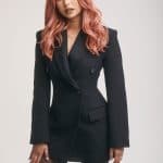 Stylish woman with pink wavy wig in black blazer and tights.