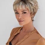 Short blonde wig with layered style and bangs, on a smiling woman.