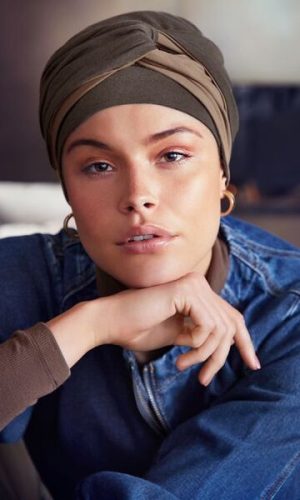 Woman wearing a stylish turban with a wig underneath, casual setting.