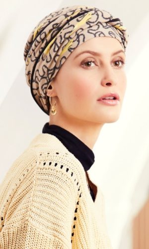 Woman wearing a stylish patterned turban and cream sweater.