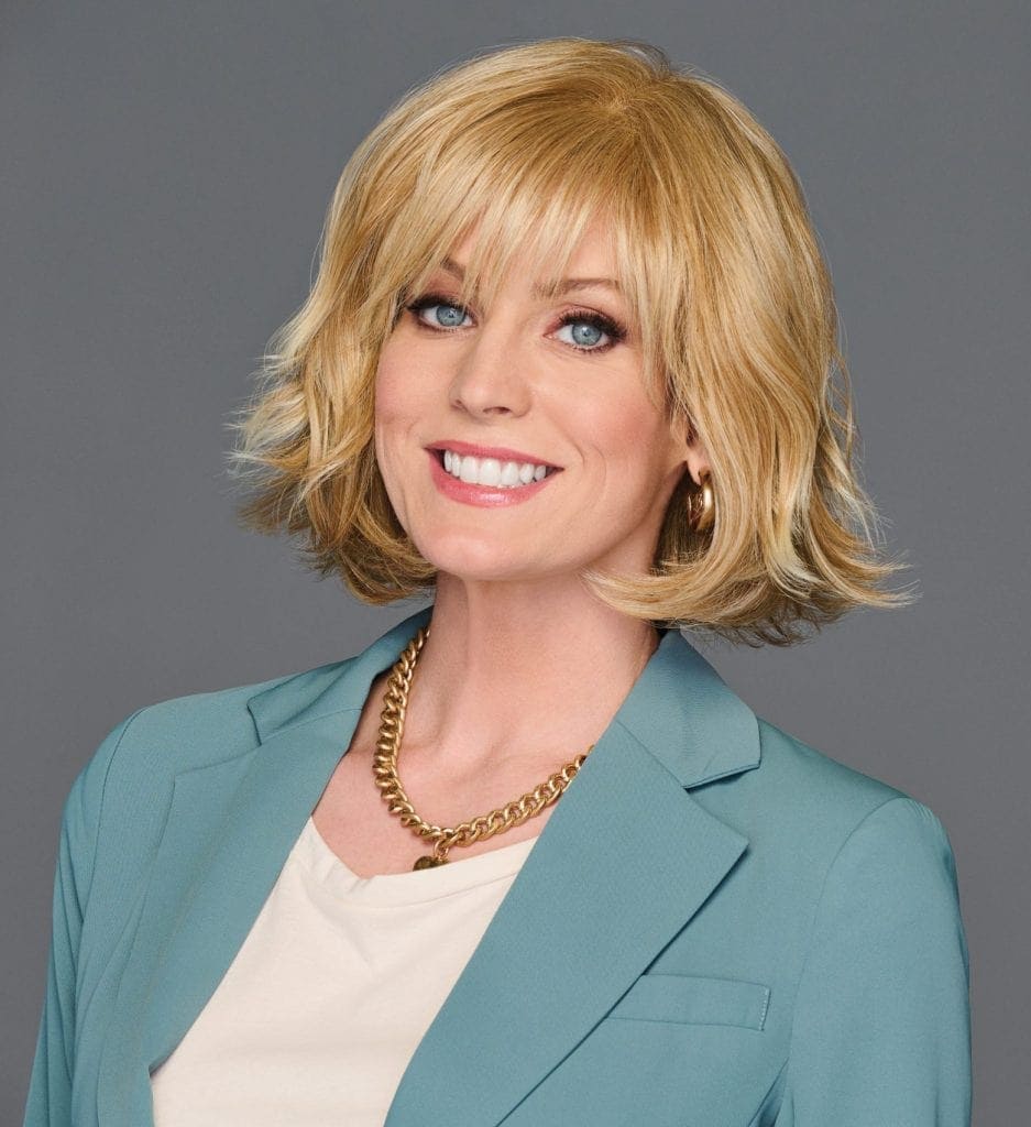 Blonde wig with layered waves on smiling woman in professional attire.