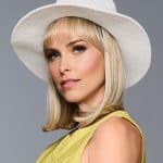 Elegant blonde woman wearing a white sun hat and yellow top showcasing a wig.