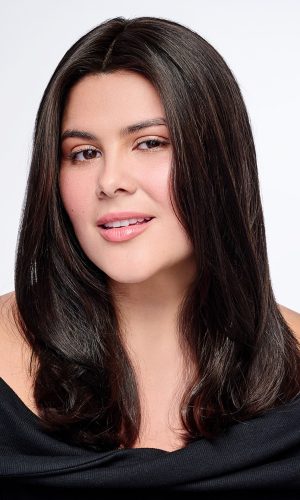 Woman with long, dark, natural-looking wig, winking at camera.