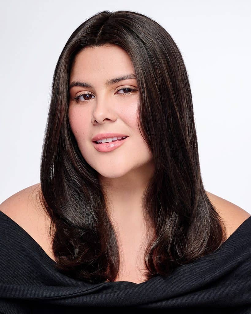 Woman with long, dark, natural-looking wig, winking at camera.