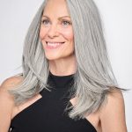 Elegant woman with long, silver hair wearing a black top.