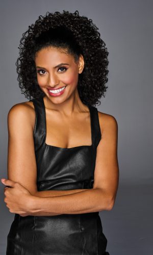 Woman with natural curly hair styled in a coily cinched ponytail.