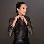Woman with braided ponytail wearing dark clothing and jewelry.
