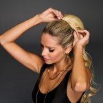 Woman with blonde Hollywood waves cinch pony hairstyle.