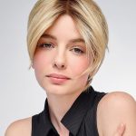 Blonde woman with short layered wig, natural look, on white background.