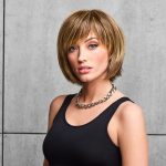 Woman wearing a short, layered blonde fringe bob wig with side-swept bangs.