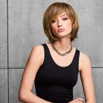 Woman with a stylish, layered blonde fringe bob wig and black tank top.